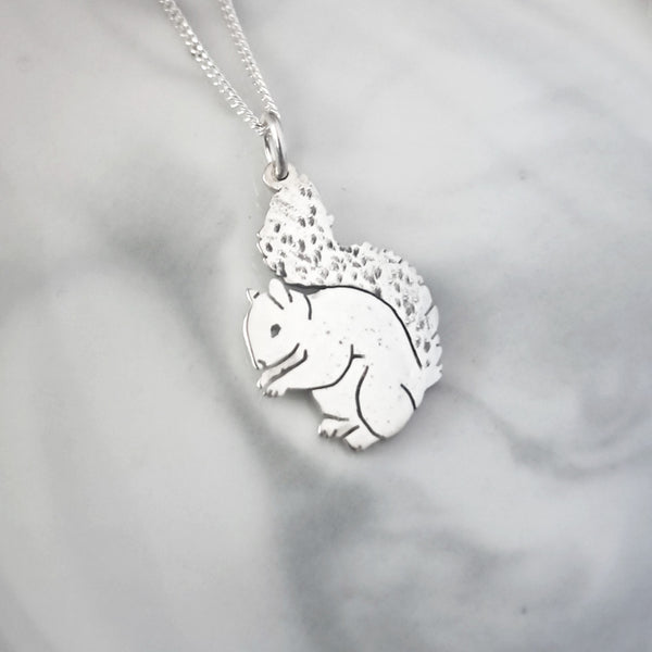 Silver squirrel pendant on a chain against a gray background