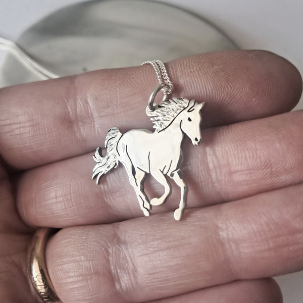 Silver horse pendant necklace on a hand