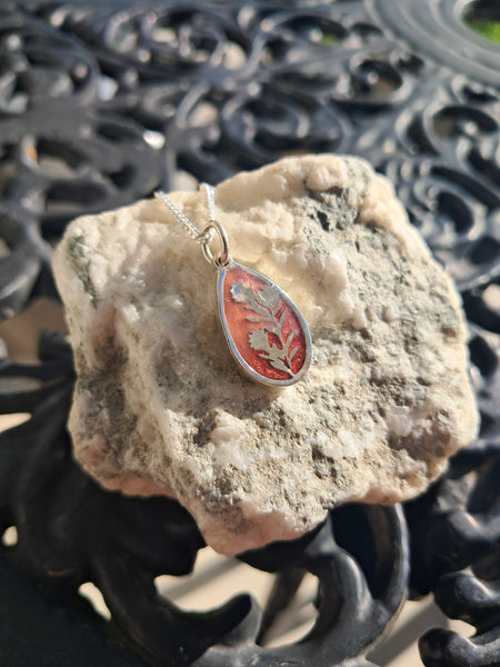 Decorative pendant on a textured stone surface with intricate metalwork in the background