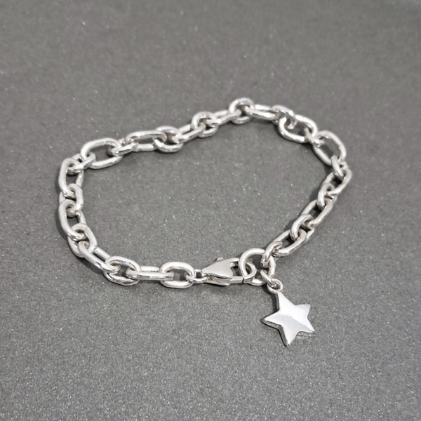 A silver chain bracelet with a small star charm, displayed on a textured dark gray background.