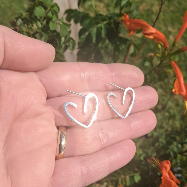 Heart hoop earrings shown on hand